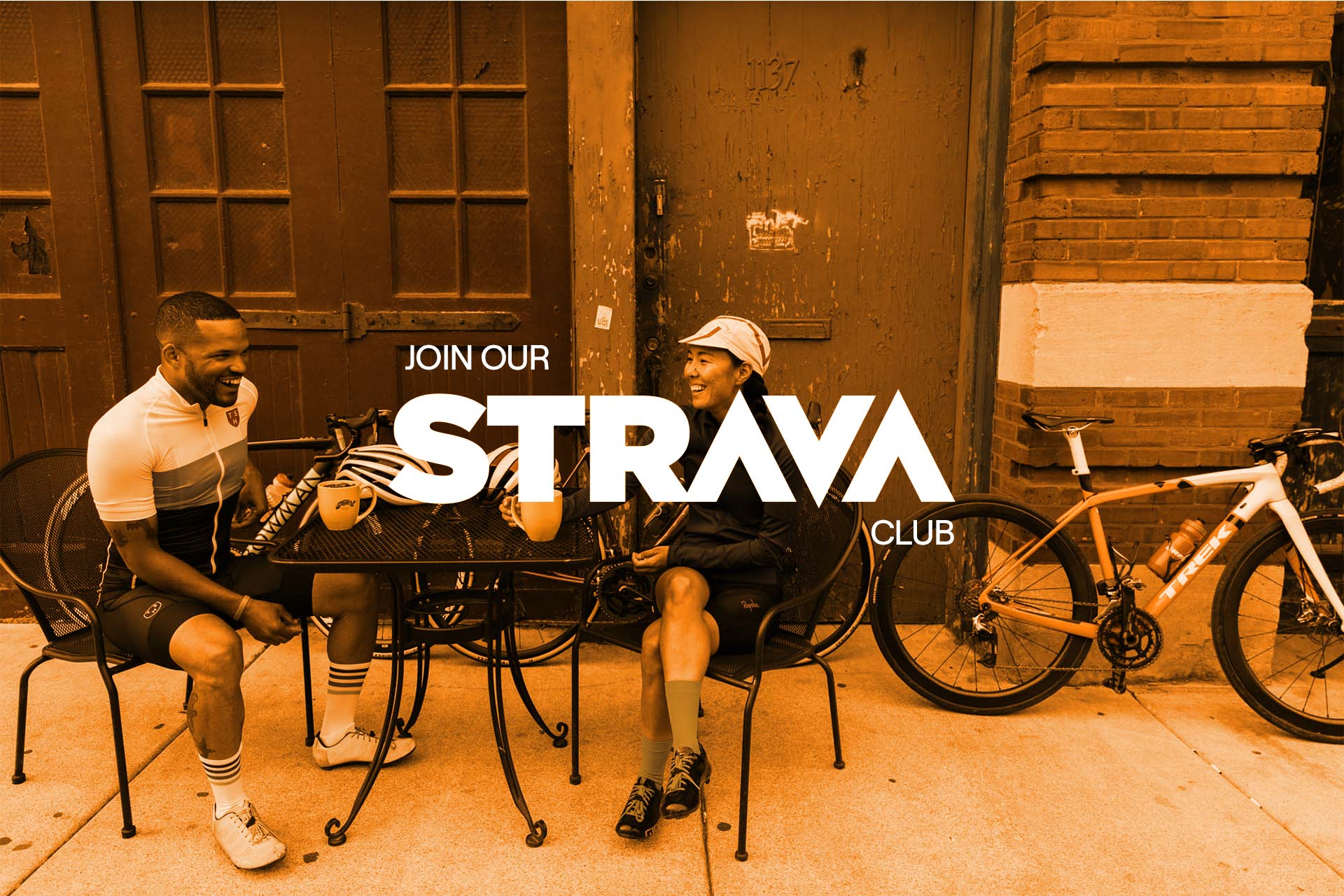 Two cyclists have a coffee at a table, with an orange overlay, with the Strava logo atop