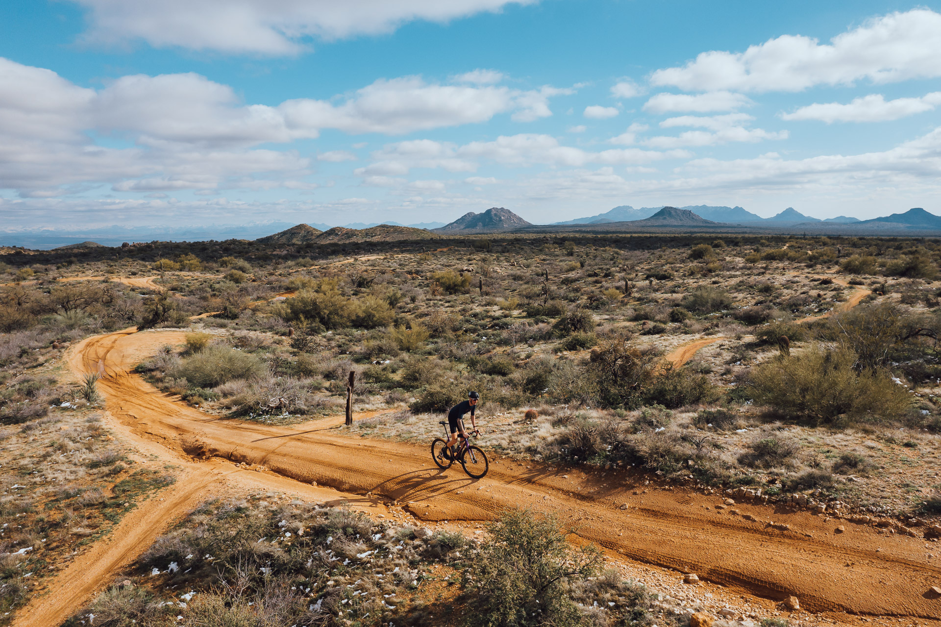 Sam Andrews cycling on a dusty red dirt path through the Arizona desert
