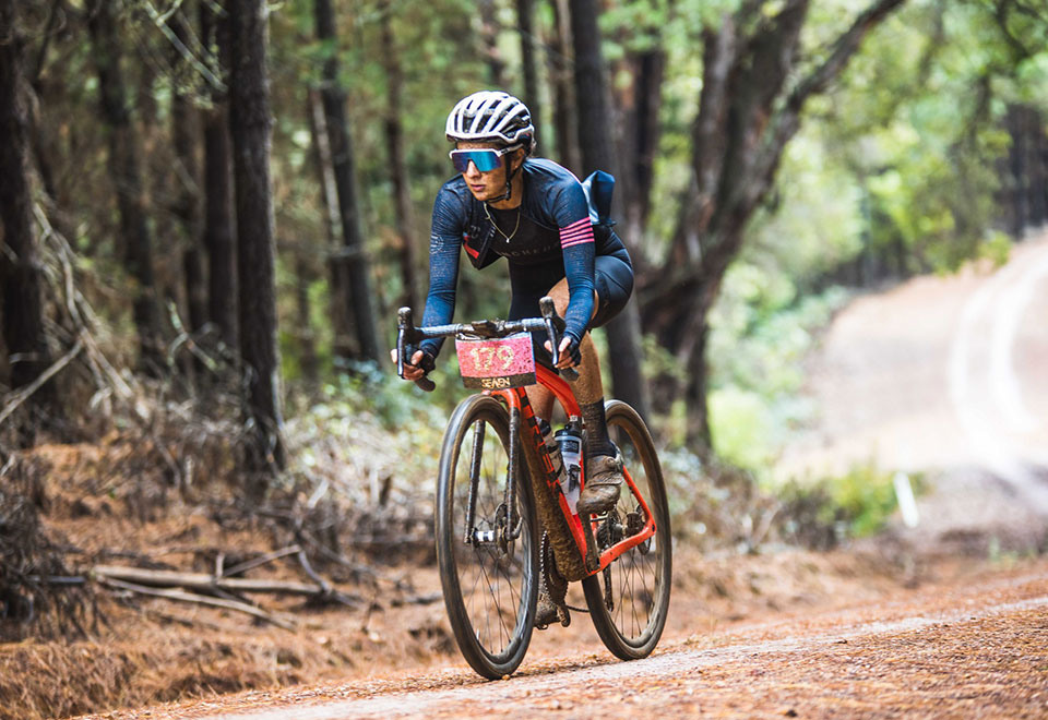 Nicole Mitsigeorgis riders her gravel bike through the forest at SEVEN Gravel