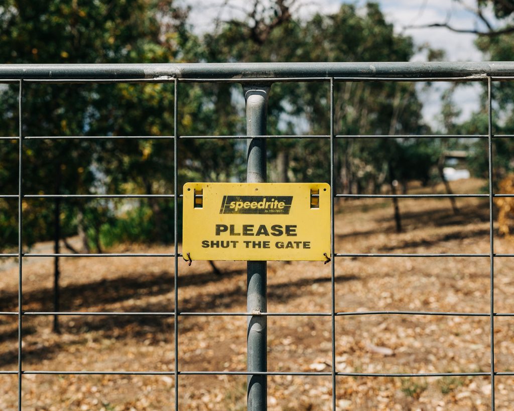 A yellow sign that says "Please shut the gate"