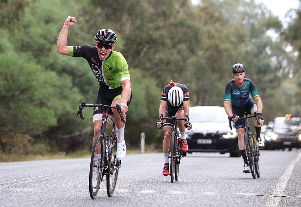 Archie is in a black and green jersey, celebrating a win of the cycling race.